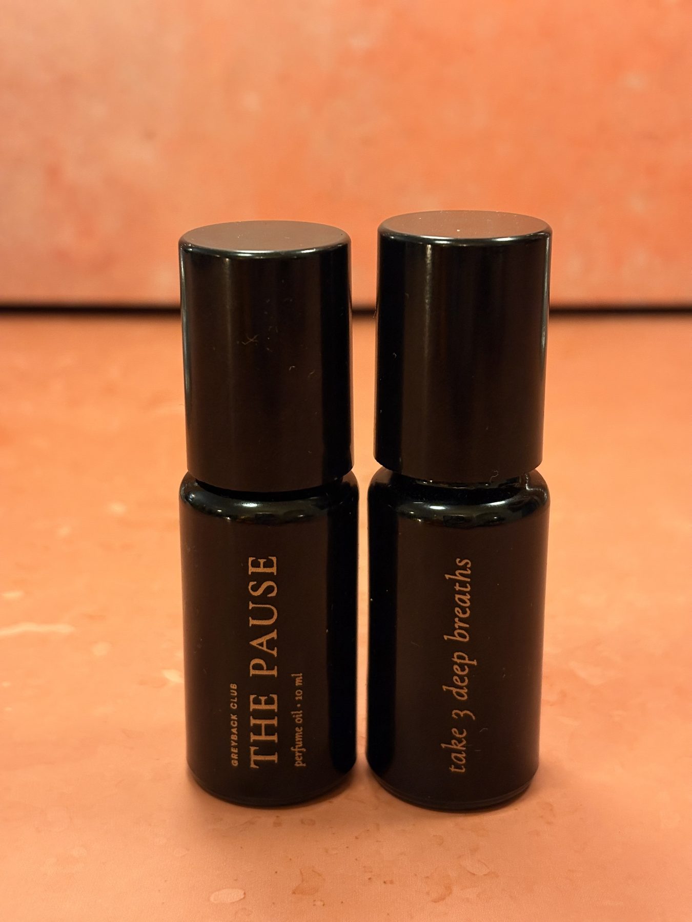 Two bottles of The Pause on a terracotta surface — one reads “take 3 deep breaths”